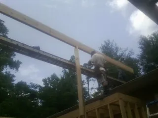 Carpenter setting a ridge beam over a new addition frame — Ice Dam Removal by Roofing Brothers in Big Bend