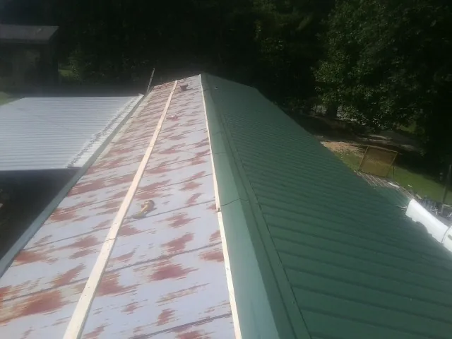 Old rusted panels beside newly installed green metal roofing — Wind Damage Roof Repair by Roofing Brothers in Big Bend