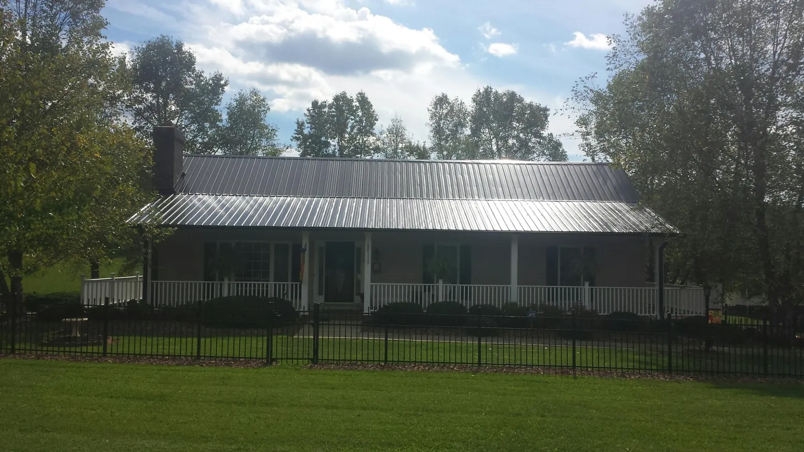 Gray metal roof on a brick ranch with a full width front porch — Gutter Guard Installation work by our crew in Big Bend